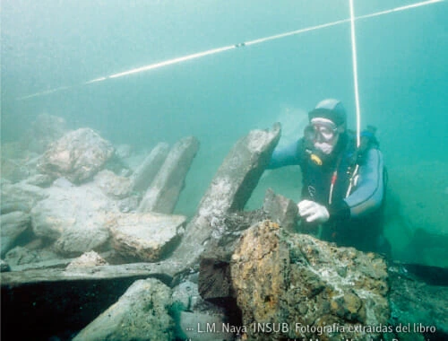 Arqueologia submarina, un buceador examina restos bajo el agua.
