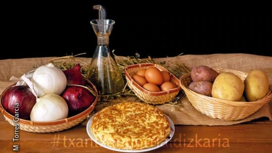 Patata-tortilla bere osagaiez inguratuta, arrautza, olioa, patatak eta tipula.